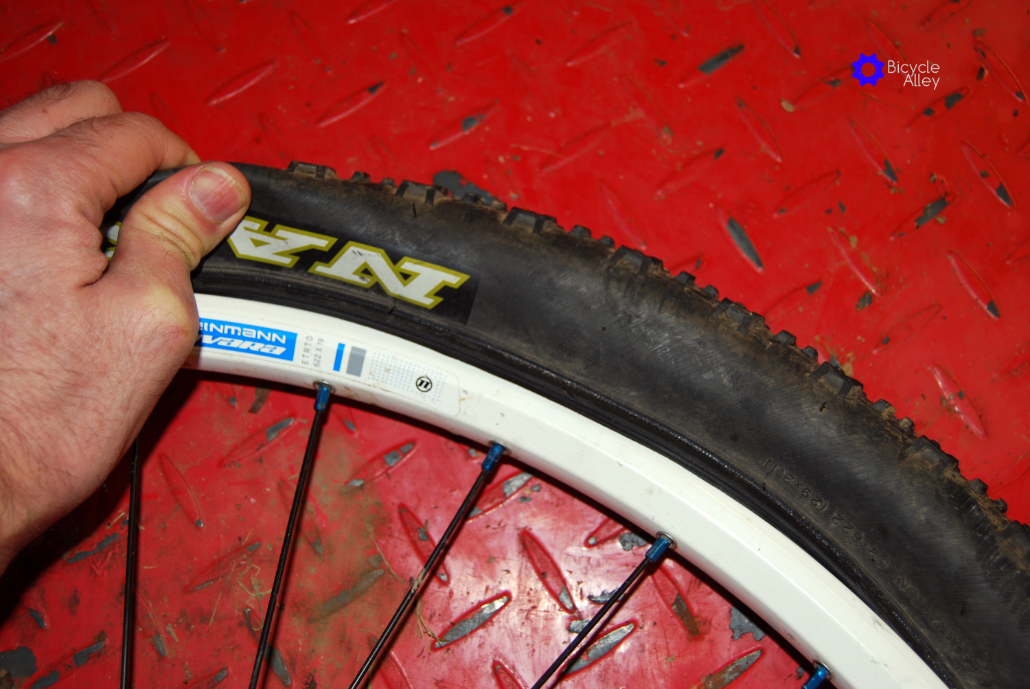 Lift tire up and out to remove tire bead from rim