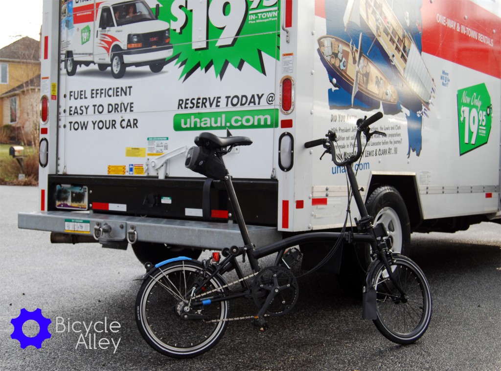 The Brompton bicycle unfolded and leaning against the U-haul 10 foot moving truck.